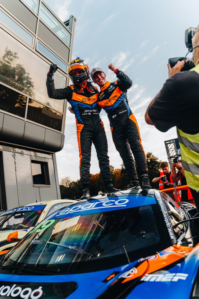 Riccardo Cazzaniga e Dean MacDonald festeggiano in piedi sulla McLaren #59 dopo la vittoria in Gara 1 a Monza